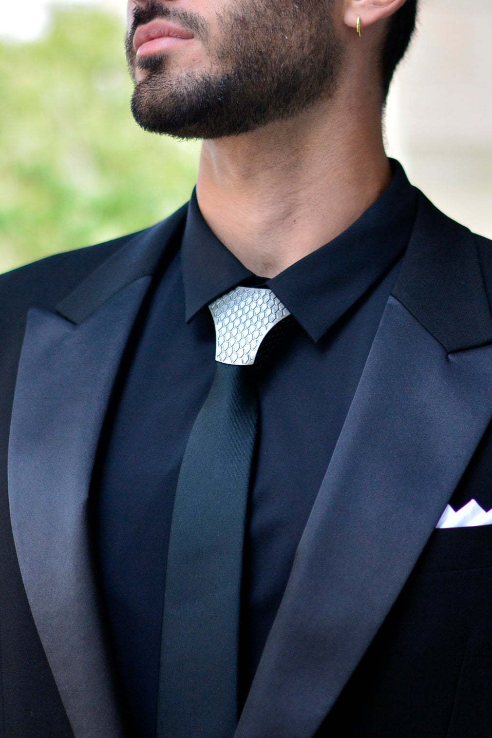 Man wearing a black tuxedo with a white pocket square and shirt collar.