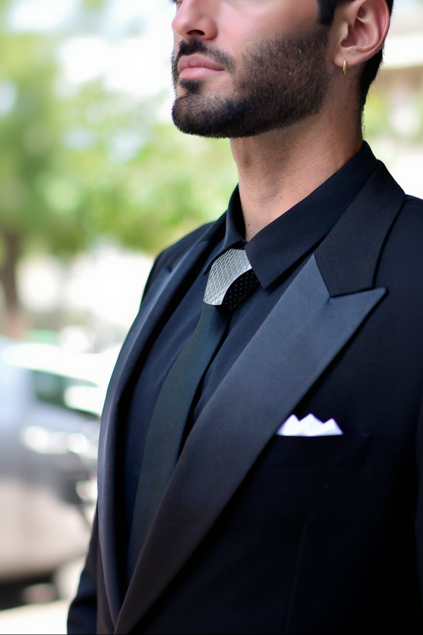 Man wearing a black suit with a white pocket square in an urban setting