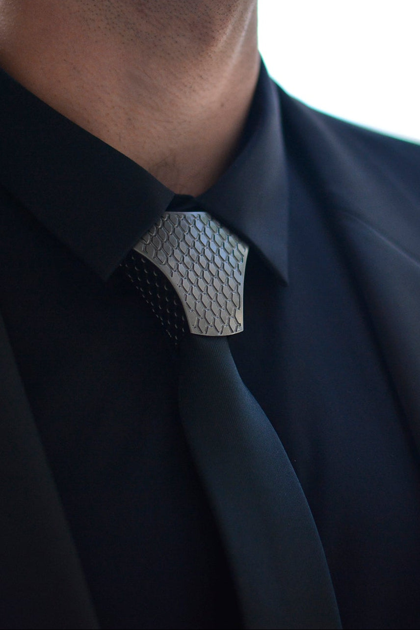 Person wearing a black suit with a patterned tie against by unities