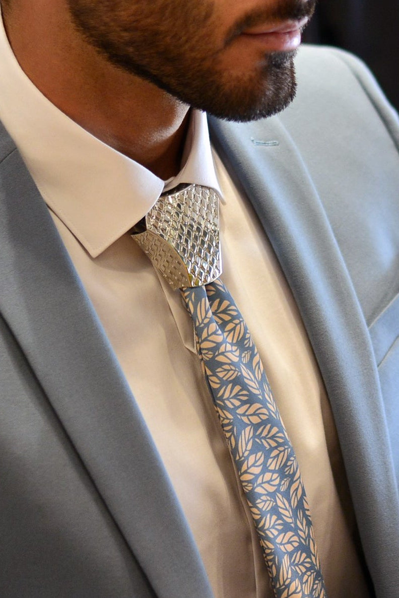 Man wearing a gray suit with a  unities jewelry patterned tie indoors