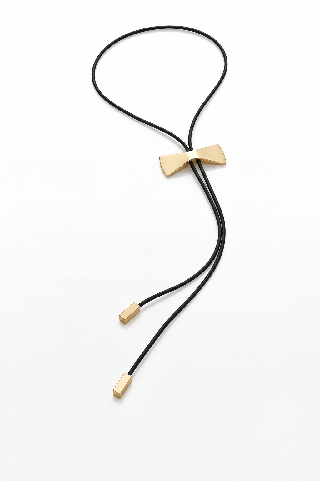 A black cord bolo tie necklace with a polished gold bow-shaped center and gold-toned metal end caps, photographed on a clean white background.