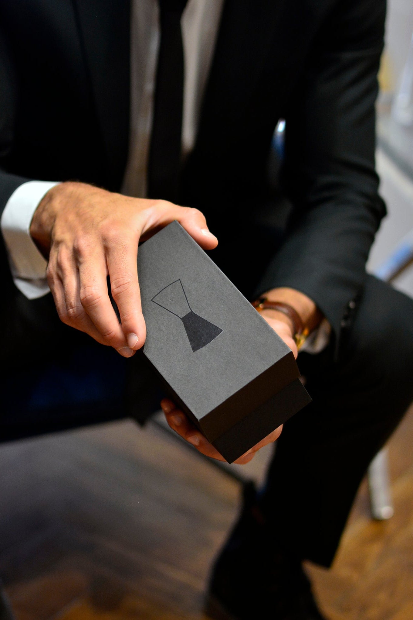 Person holding a black box with a logo in an indoor setting
