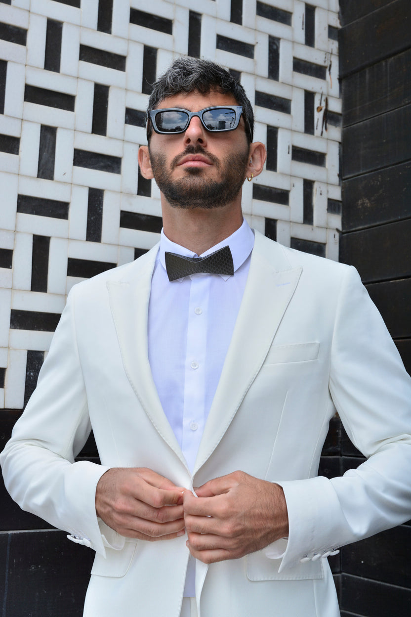 Man wearing a white suit and bow tie by unities on a black and white patterned