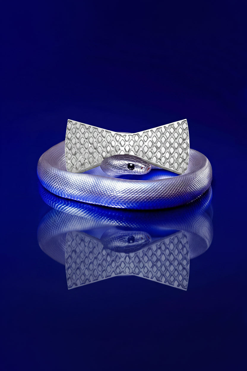 Silver snake-shaped bow tie with textured surface on a reflective blue surface